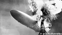 ARCHIV - Der hintere Rumpfteil des Luftschiffs LZ 129 Hindenburg wird am 6. Mai 1937 bei der Landung auf den Luftschiffhafen von Lakehurst bei New York von einer Explosion erschüttert. Insgesamt 36 Passagiere und Besatzungsmitglieder kamen bei der Katastrophe ums Leben. Der 100 Tonnen schwere, zu seiner Zeit größte Zeppelin der Welt brannte völlig aus. dpa (zu lsw Korr: «Das Kleid des Mädchens brannte schon» - Aufzeichnungen des Zweiten Offiziers auf der Hindenburg vom 04.05.2012) +++(c) dpa - Bildfunk+++ *** Die Katastrophe Zehn Rundfahrten zwischen Deutschland und den USA und sieben nach Rio de Janeiro sollte das Luftschiff unternehmen. Dann, am 6. Mai 1937, geschah während des Andockens am Landemast in Lakehurst das Unglück: Das Heck der Hindenburg ging plötzlich in Flammen auf. Unser Foto zeigt den Moment unmittelbar nach der ersten Explosion. ***