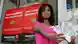 A woman holding a bunch of banknotesd in front of a Moneygram sign