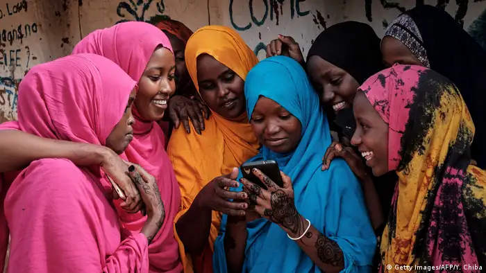 A group of Somali refugee women look at a smartphone as they stand together at Dadaab refugee complex in the north-east of Kenya
