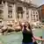 A tourist throws a coin into the Trevi fountain