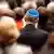 A man seen from behind wearing a blue-and-white yarmulke. The people around him are out of focus. Cologne, June 6, 2019.