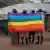 Les membres de la communauté LGBTQ portant un drapeau arc-en-ciel.