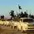 Kamyonetlerden oluşan bir araç konvoyunda, elleri silah ve bayraklı IŞİD militanları