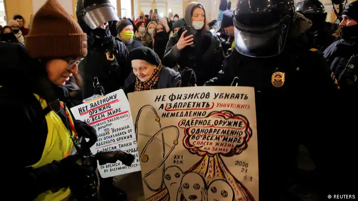 Law enforcement officers escort an elderly artist and activist, Yelena Osipova, during an anti-war protest