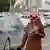 A Saudi man smokes a cigarette and reads something on his mobile phone in Riyadh