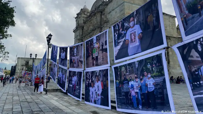 The DW Akademie- suported photo project hangs in a busy square in front of a church.