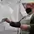 Женщина в защитной маске опускает лист бумаги в ящик с надписью "Референдум" в Мелитополе
