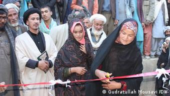 A woman cuts the ribbon for the opening of a library in Daikundi