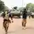 Soldiers escort a military convoy down a road in Ouagadougou, Burkina Faso