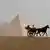 Tourists ride a horse-drawn cart in front of the Pyramids in Giza, on the outskirts of Cairo, Egypt.