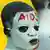 A boy has his face painted white with the word AIDS in red on his forehead