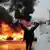 İran'daki protestolar sırasında yanan lastiklerin önünde bir kadın