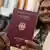 Une femme brandit fièrement son passeport allemand nouvellement acquis devant l'objectif du photographe (illustration)