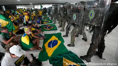 Bolsonaro supporters sit in front of police officers at Palacio do Planalto