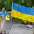 Female Protester with a large Ukraine flag that has the words Exit Gas, Stop War painted on it