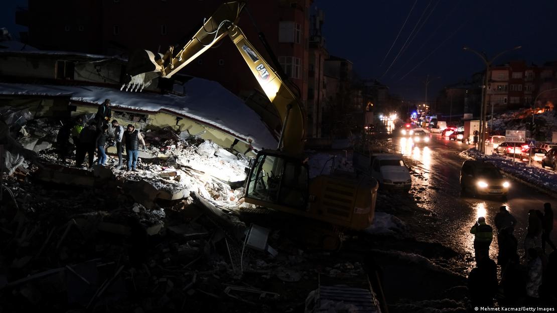 Depremin ardından Kahramanmaraş'ın Elbistan ilçesinde, bir enkazın üstünde, gece karanlığında, iş makinesinin de katılımıyla sürdürülen çalışmalar - (07.02.2023)