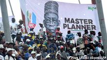 upporters sit beside a banner of presidential candidate of All Progressives Congress (APC) Bola Tinubu during the party campaign rally at Teslim Balogun Stadium in Lagos, on November 26, 2022. 