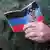 Ein Mann hält Papiere der sogenannten "Volksrepublik Donezk" mit deren Fahne und Wappen in der Hand