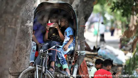 Children play games on smartphones as they sit in a Rickshaw in Dhaka, Bangladesh
