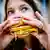  A woman eats fries and a hamburger at a fast food restaurant