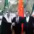 Three men in front of the Saudi, Chinese and Iranian flags; two are shaking hands