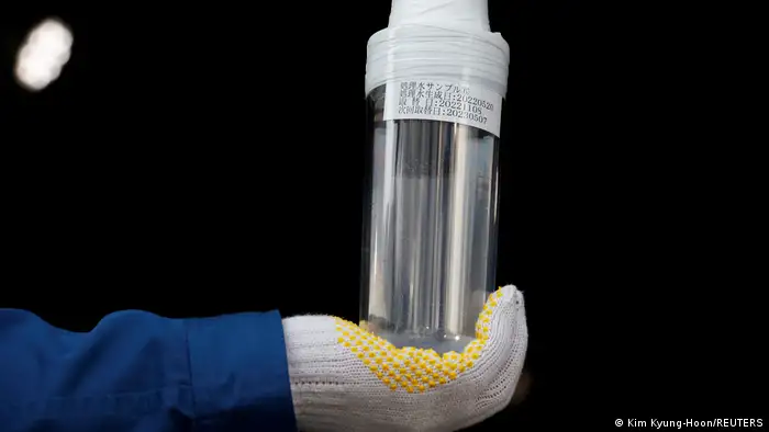 A Tepco employee holds a sample of treated water up to the camera