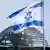 An Israeli flag flies with a glass dome of the German Bundestag in the background