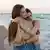 A lesbian couple at the beach, hugging gently