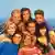 Film still from 'Beverly Hills 90210': 8 young people bunched together, smiling for a group photo.
