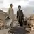 Dva dječaka u Afganistanu s posudama za nošenje materijala pored netom napravljenih cigli
