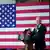 Presidente americano Joe Biden fala ao microfone diante de bandeira dos EUA