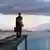 A man in a suit holding a briefcase looking at a lake
