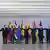 Líderes de 11 países de mãos dadas em frente às bandeiras de seus países