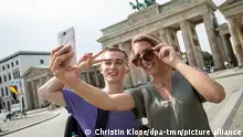 ILLUSTRATION - Eine Frau und ein Mann stehen am 13.08.2020 in Berlin vor dem Brandenburger Tor und machen ein Selfie (gestellte Szene). Foto: Christin Klose || Modellfreigabe vorhanden