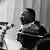 Martin Luther King de profil, devant des micros, prononçant son discours "'I have a dream", le 28 août 1963