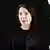 Marina Abramovic, portrait of a woman with a dark background, circled by luminous blocks forming a portal.