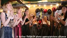 图中，女性们穿着传统服饰dirndl紧身连衣裙，正在享受慕尼黑啤酒节