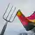 A pitch fork piercing a German flag