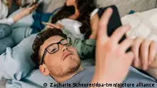 ILLUSTRATION - Medienzeit bei Teens, die Geschwister sitzen oder liegen auf der Couch im Wohnzimmer am 25.05.2023 in Berlin mit ihren Handys in der Hand, sie verbringen Zeit in den unterschiedlichsten Sozialen Netzwerken oder unterhalten sich (gestellte Szene). Foto: Zacharie Scheurer || Modellfreigabe vorhanden || Modellfreigabe vorhanden