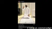 吕迪格发布的具有争议性的Instagram帖子，照片中他身着白袍、跪在祈祷垫上、右手食指指向上方
