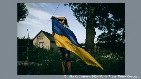 Ein Junge hält die ukrainische Flagge vor sich.